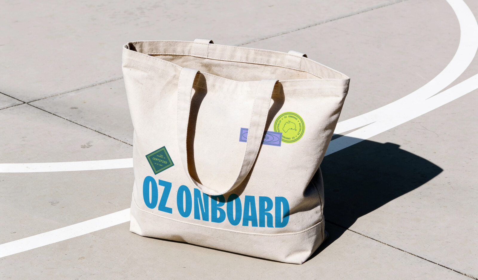 A canvas tote bag featuring the slogan OZ ONBOARD in large blue letters and three decorative stickers, reflecting a personalised property marketing campaign.