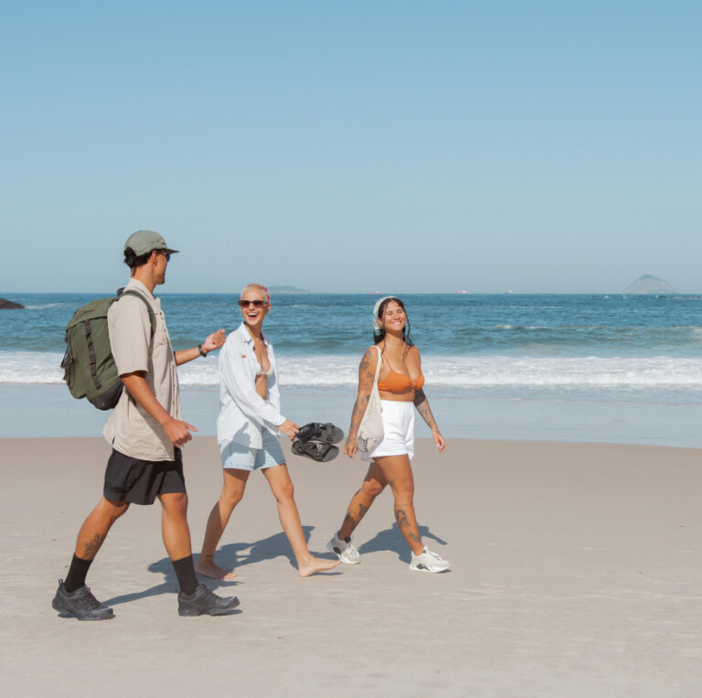 Three friends walk along a sandy beach near the sea, mirroring the adaptive nature of a personalised property marketing campaign.