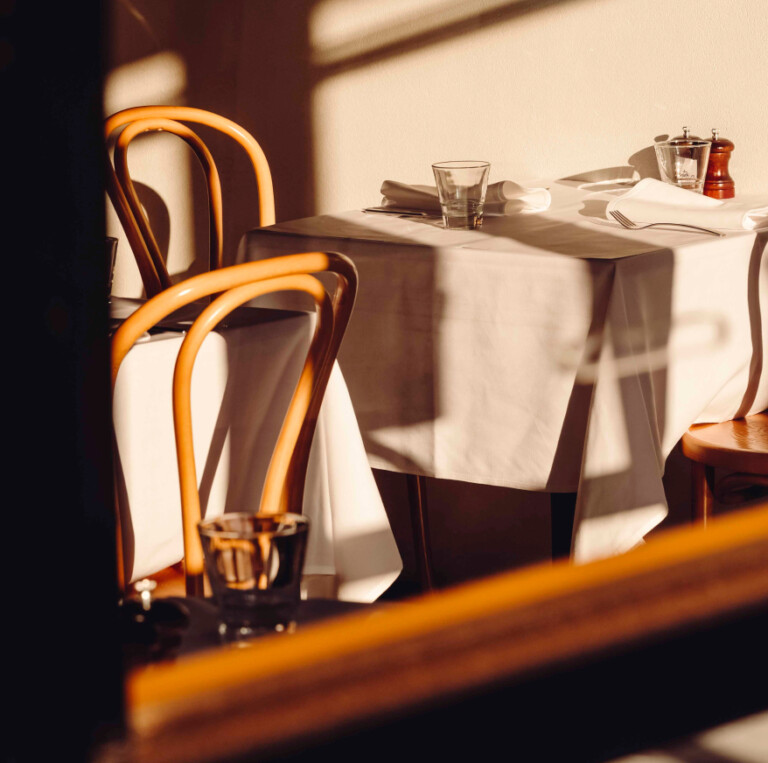 Sunlit restaurant featuring tables with white tablecloths and wooden chairs, designed for a personalised property marketing campaign adapting in real time.