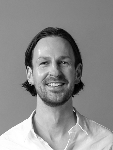 Headshot of a smiling man with shoulder-length hair wearing a collared shirt.