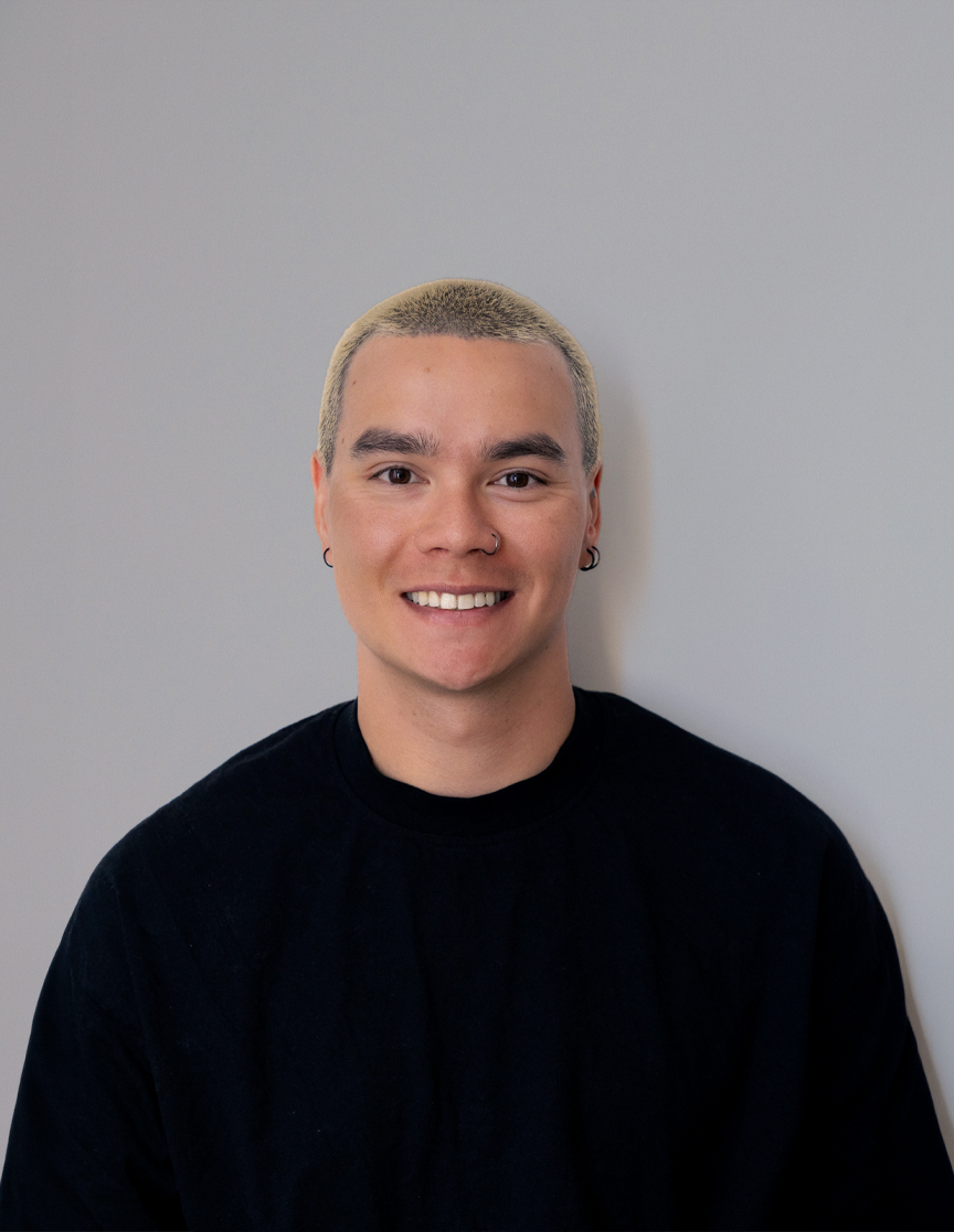 A person with short, blonde hair and a nose ring smiling at the camera.